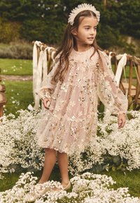 Õiekujulise mustriga, läbipaistev roosa kleit mitmekordsete kihtidega ja liibuva varrukaga, kaunistatud litritega. Sobitatud heledate roosade kingade ja peapaelaga.