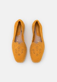 Dzelteni zamšaini slip-on apavi ar lāzergrieztiem ziedu motīviem, paršūtiem akcentiem un elastīgu zoli, kas izstrādāti komfortam un gaisa caurlaidībai.