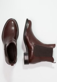 Braune Leder-Ankle Boots mit elastischen Seitenteilen und niedrigem Absatz. Glatte Oberfläche und rundes Zehendesign. Robuste Gummisohle mit strukturiertem Profil.