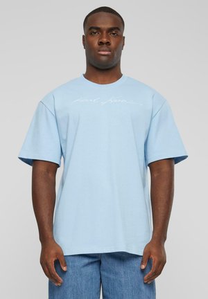 Ljusblå oversized t-shirt i bomull, med korta ärmar och rundad halsringning, förslagen med vit skriptlogga på framsidan.