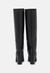 Czarne skórzane kozaki do kolan o gładkim wykończeniu, z pionowymi szwami i masywnymi obcasami.