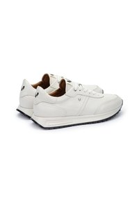 Zapatillas de cuero blancas con un perfil bajo, punta redonda y suela acolchada. Cuentan con acentos del logo en negro y una textura suave.