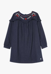 Granatowa sukienka z długim rękawem z czerwonymi i białymi haftami kwiatowymi na dekolcie oraz falbanami na klatce piersiowej i ramionach.