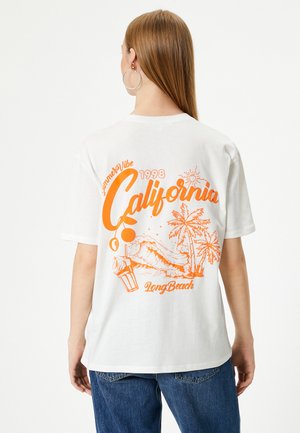 Hvid T-shirt med levende orange grafisk tekst og strand-tema illustrationer på ryggen, med en løs pasform og korte ærmer.