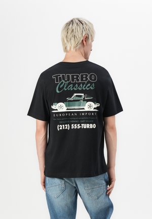 T-shirt en coton noir avec un imprimé graphique au dos représentant une voiture verte, du texte "TURBO Classics" et des coordonnées en blanc.