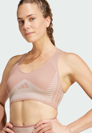 Sostén deportivo de color rosa claro, hecho de tela texturizada. Presenta un patrón geométrico, un diseño de espalda de nadadora y un logo en la banda.