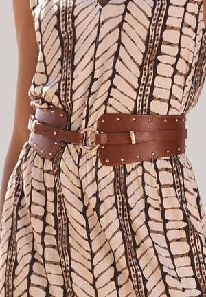 Brauner Ledergürtel mit goldfarbenen Beschlägen, verziert mit Nieten und einer runden Schnalle. Getragen über einem gemusterten Kleid in neutralen Tönen.