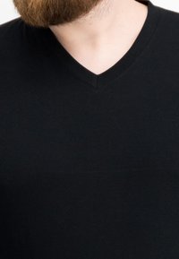 Schwarzes Baumwoll-V-Ausschnitt-T-Shirt mit glattem Stoff, figurbetontem Schnitt und kurzen Ärmeln; keine sichtbaren Muster oder Akzente.