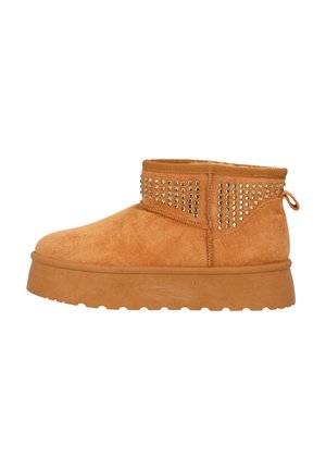 Stivale alla caviglia in suede beige con superficie texture, dettagli con borchie lungo la parte superiore e suola in gomma spessa per una buona aderenza.