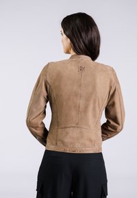 Giacca in camoscio marrone con un design aderente, caratterizzata da una superficie texturizzata e sottili dettagli di cucitura, mostrata da dietro.
