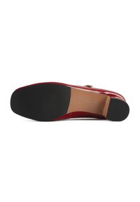 Red patent leather high heel shoe with a smooth finish, pointed toe, and a black rubber sole featuring a grooved texture for grip.