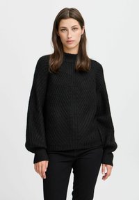 Zwarte gebreide trui met een hoge hals, geribbelde textuur en brede mouwen. De stof lijkt dik en comfortabel, met gedetailleerde diagonale patronen.