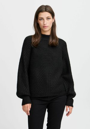 Maglione nero lavorato a maglia con collo alto, texture a costine e maniche larghe. Il tessuto appare spesso e accogliente, con dettagli di motivi diagonali.
