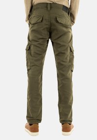 Olijfgroene cargobroek met een slim fit, voorzien van meerdere zijzakken en een gestructureerde stof. Van de achterkant getoond met bruine sneakers.