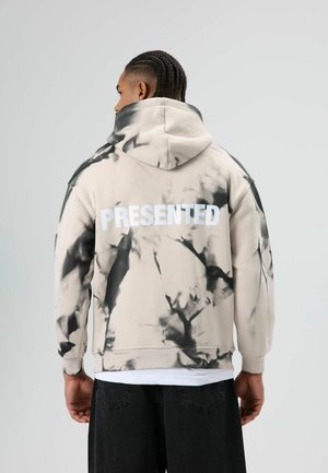 Beige hoodie met zwart abstract patroon en witte tekst "PRESENTED" op de achterkant. Gemaakt van katoen, met een losse pasvorm.