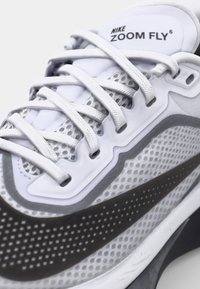 Nike Zoom Fly 6 sneakers med et grått og hvitt mesh-overdel, flate hvite snørebånd, teksturerte mønstre og en svart detalj ved mellomsålen.