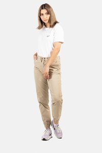 Pantalones cargo beige con puños elásticos, camiseta de algodón ligera en blanco con pequeño texto negro, y zapatillas con detalles en púrpura.