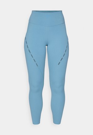 High-waisted, light blue leggings made of stretch fabric. Features decorative cut-outs along the sides and fitted ankle cuffs.