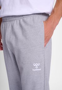 Graue Sweatpants mit elastischem Bund und seitlichen Taschen. Mit gesticktem Logo in Weiß. Weicher Baumwollmischgewebe.