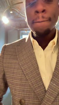 Blazer à carreaux marron et blanc avec une fermeture à double bouton sur une chemise beige clair. Tissu doux avec une coupe ajustée, col visible.