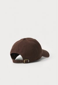 Casquette de baseball en coton marron avec une visière incurvée, fermoir métallique réglable et détails cousus. Présente un design à l'arrière fermé.