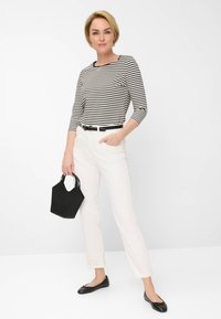 Stribet sort og hvid langærmet top, hvide bukser, sort bælte, sorte flade sko og en lille sort taske. Glat stof, slim fit.