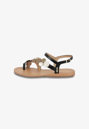 Sandali piatti neri con un design a ritaglio e accentuazioni in metallo circolare. La suola è color beige con una texture liscia e una cintura con fibbia.
