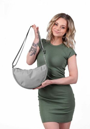 Šedá polo-měsíční taška vyrobená z hladkého materiálu, s úzkým popruhem a minimalistickým designem. Taška má decentní kovové detaily a žádné viditelné zdobení.