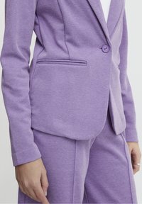 Lila strukturerad blazer med en knapp, skräddarsydd passform och sidfickor, i kombination med matchande byxor. Fint detaljerad tygstruktur.