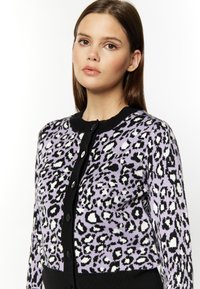 Cardigan lilla con stampa leopardata bianco e nero, colletto a coste nero e chiusura con bottoni, dotato di bottoni neri e silhouette aderente.