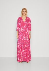 Lång rosa blommig klänning med djup V-ringning, trekvartslånga ärmar och en volangkjol med djärva rosa och mjuka röda mönster.