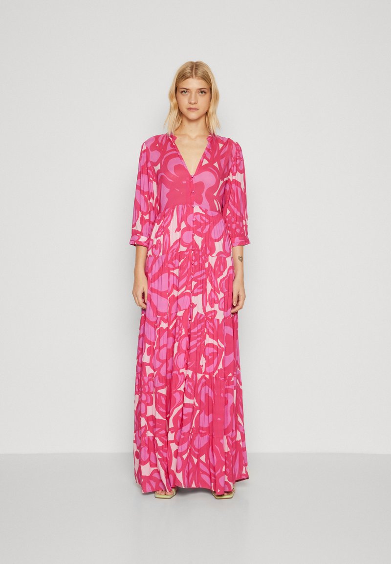 Lång rosa blommig klänning med djup V-ringning, trekvartslånga ärmar och en volangkjol med djärva rosa och mjuka röda mönster.