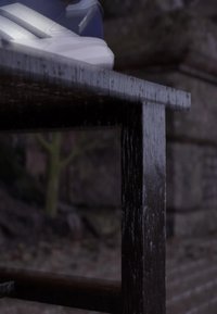 Bílo-modrá sportovní bota s nápisem "Duramo Speed" spočívá na okraji tmavého dřevěného stolu venku.