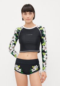 Long-sleeve black rash guard with floral sleeves; matching black swim shorts with floral accents. Made from stretchy, quick-drying fabric.