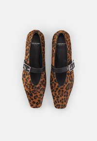 Paire de chaussures pour femmes à imprimé léopard, bout carré, avec des brides à boucle noires et des semelles intérieures noires, vues de dessus sur fond gris.