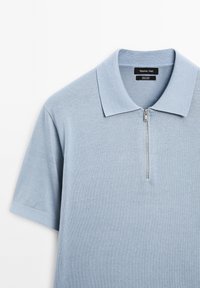 Polo en coton bleu clair à manches courtes avec une fermeture éclair au col, étiqueté Massimo Dutti.
