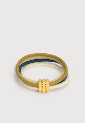 Τρία τυλιγμένα δερμάτινα βραχιόλια σε μπεζ, μπλε και ελιά χρώματα, συνδεδεμένα με μια λαμπερή χρυσή αγκράφα σε λευκό φόντο.