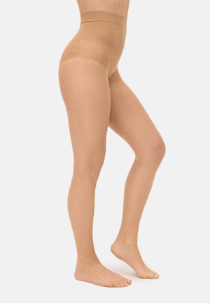 Piernas con medias transparentes color nude de cintura alta, colocadas sobre un fondo blanco, un pie apoyado completamente y el otro con el dedo del pie apuntando.