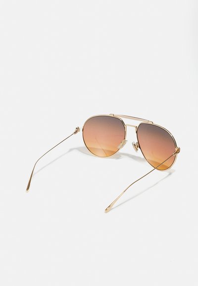 Ochelari de soare aviator aurii cu lentile degradate maro. Cadru din metal, brațe subțiri și suporturi pentru nas reglabile. Design minimalist și textură reflectorizantă.