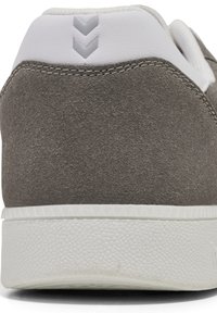 Gray suede sneaker heel with white synthetic accent, featuring three gray chevron details, textured white rubber sole with grip pattern.