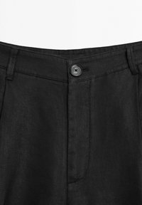 Svarta byxor med knappstängning, vikbar midja och textil med en slät finish. Platt front med sidofickor.