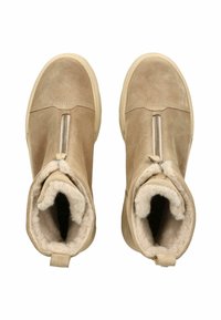 Botas de tobillo de ante beige con cierre de cremallera, forro de piel suave y suela texturizada beige. Diseño minimalista con tiradores en la parte posterior.