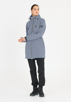 Long gray jacket with a zip front, hood, and side pockets. Features elastic cuffs and a logo patch on the sleeve. Worn over black pants and boots.