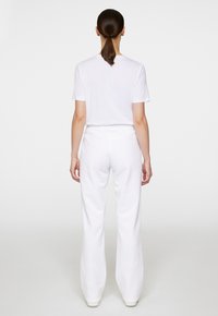 Vit t-shirt med korta ärmar och lösa vita mjukisbyxor, båda gjorda av mjukt material, med elastisk midja och en avslappnad passform.