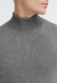 Grå turtleneck sweater lavet af blødt strikmateriale, med en tætsiddende pasform og ribbet krave, med en glat tekstur og uden synlige mønstre.
