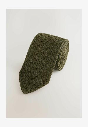 Grüne, gerollte Strickkrawatte mit texturiertem Muster und spitzem Ende. Hergestellt aus einem flexiblen Material mit matter Oberfläche.