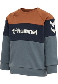 Blå, brun och grå färgblockströja med rund urringning, sidoknappar och vit logotyp på framsidan. Mjuk känsla, avslappnad passform.