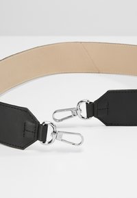 Ceinture en cuir noir avec une texture lisse et mate, dotée de clips métalliques argentés et d'une doublure intérieure beige contrastante.