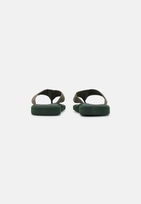 Green slide sandals with two textured straps, a sturdy footbed, and a flat rubber sole; versatile design suitable for casual wear.