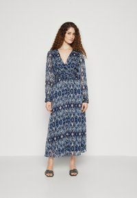 Rochie lungă, fluidă, cu un model albastru și crem, având un decolteu adânc în V, mâneci lungi din material transparent și o talie strânsă.